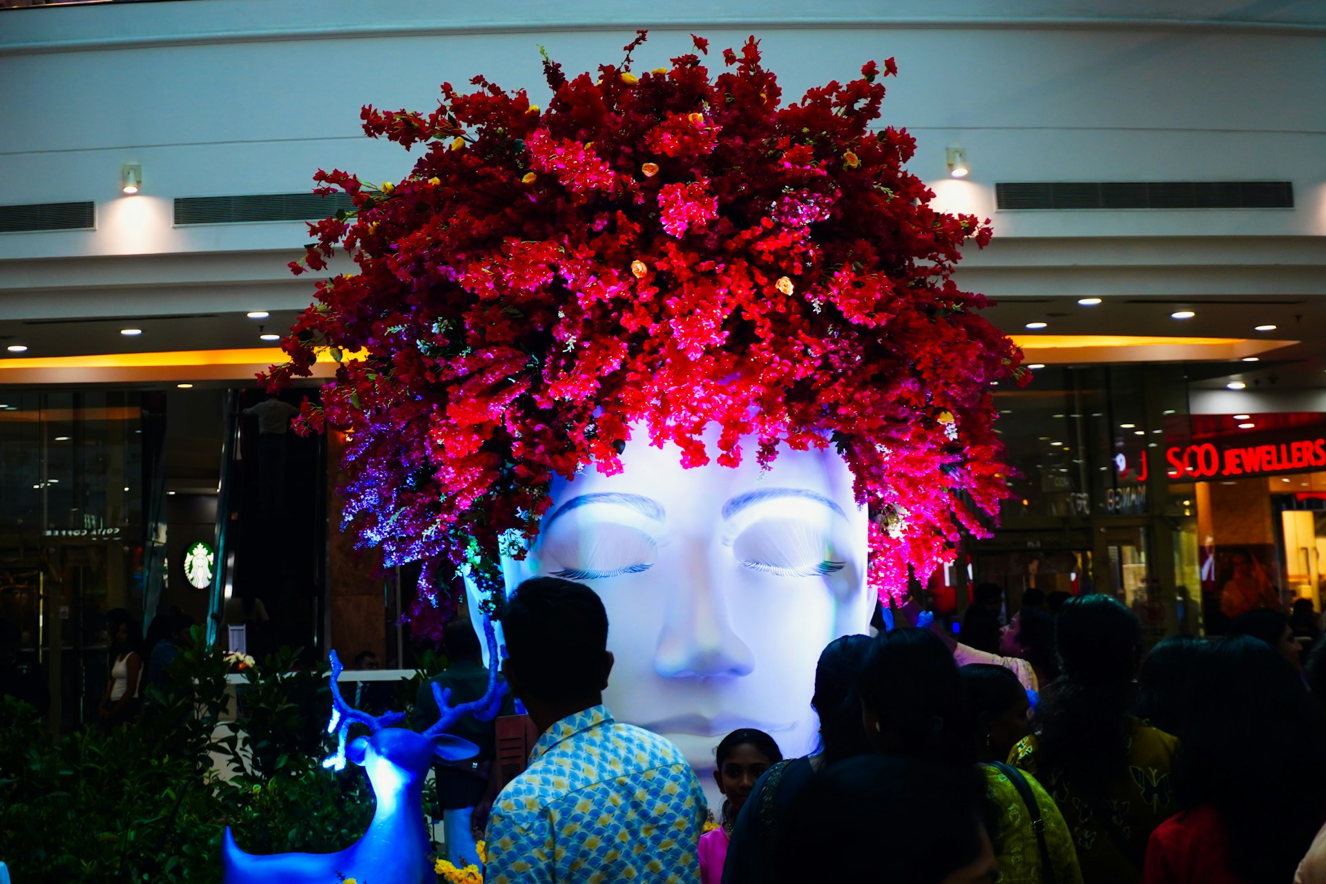 Large illuminated head sculpture with red flowers